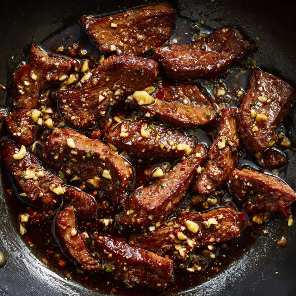 Beef sizzling in a wok with garlic and soy sauce