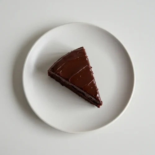 Slice of rich chocolate cake on a white plate.